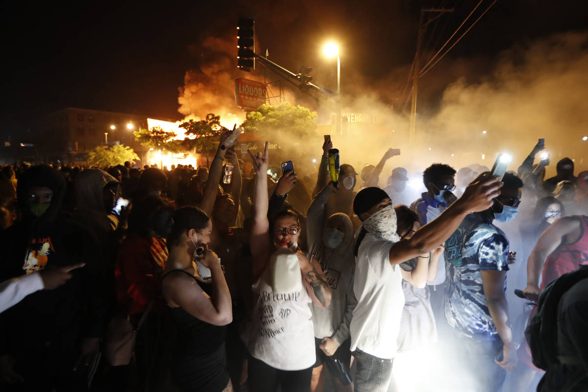 Protesters gather in front of the burning 3rd Precinct building of the Minneapolis Police Depar ...
