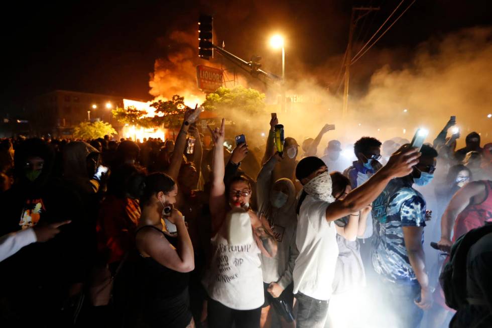 Protesters gather in front of the burning 3rd Precinct building of the Minneapolis Police Depar ...