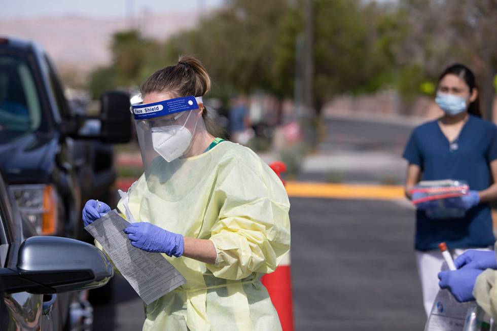 A volunteer prepares to swab a patient's nose as part of the test for COVID-19 at Calvary Chape ...