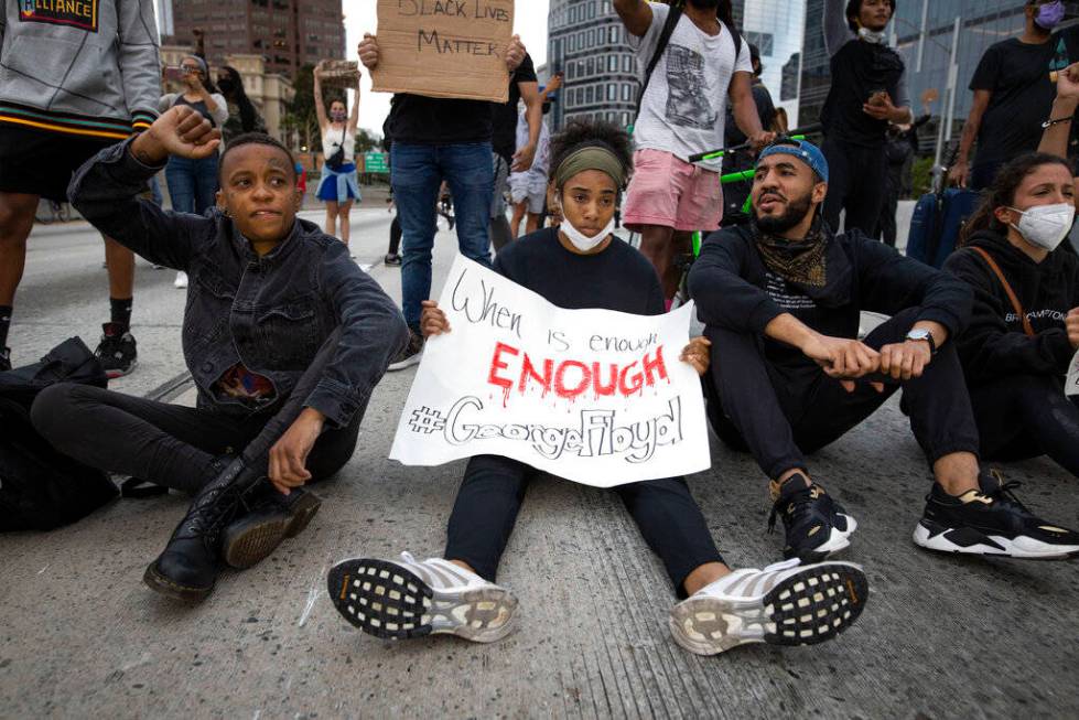 Protesters sit in the street in Los Angeles, Friday, May 29, 2020, in protest over the death of ...