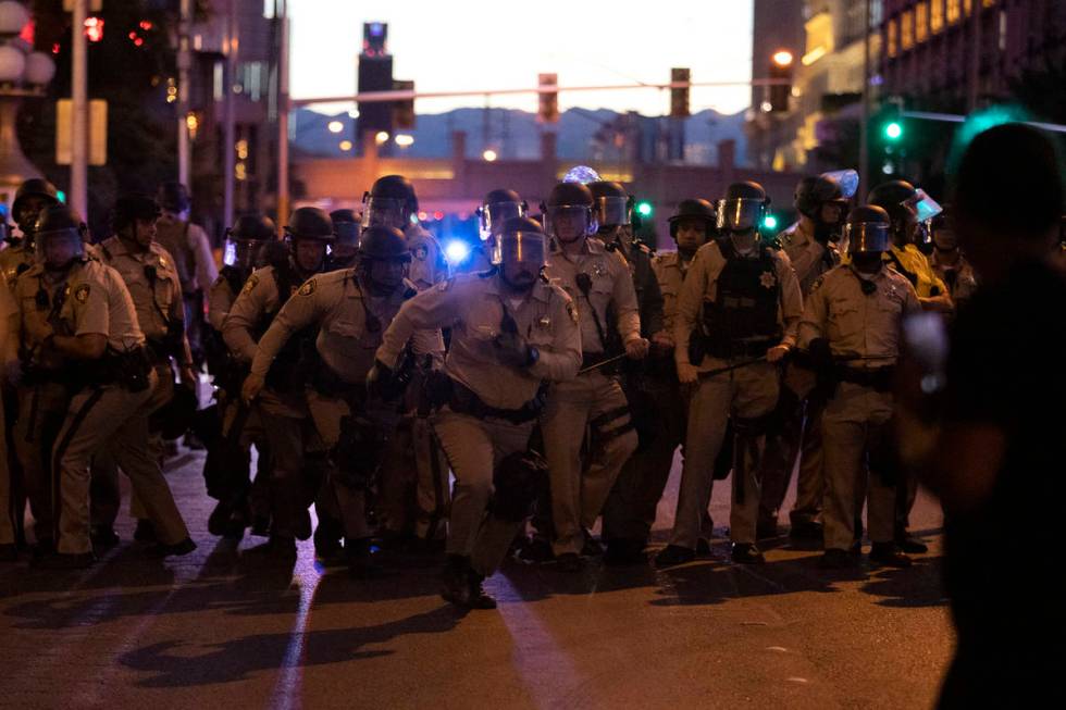 Las Vegas police officers run toward the crowd of protesters who took the Las Vegas Strip in su ...