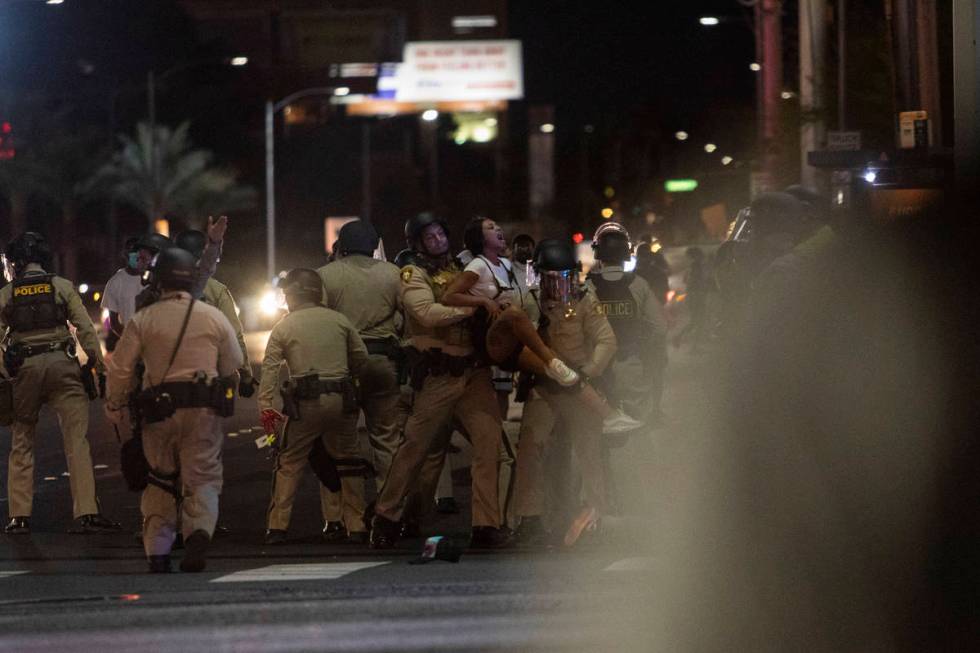 A woman is seized by several police officers from the sidewalk during a protest that ended at t ...