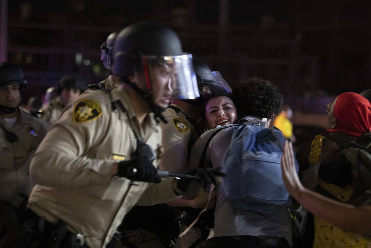 A protester is swept away as Las Vegas police descend on a gas station parking lot at Flamingo ...