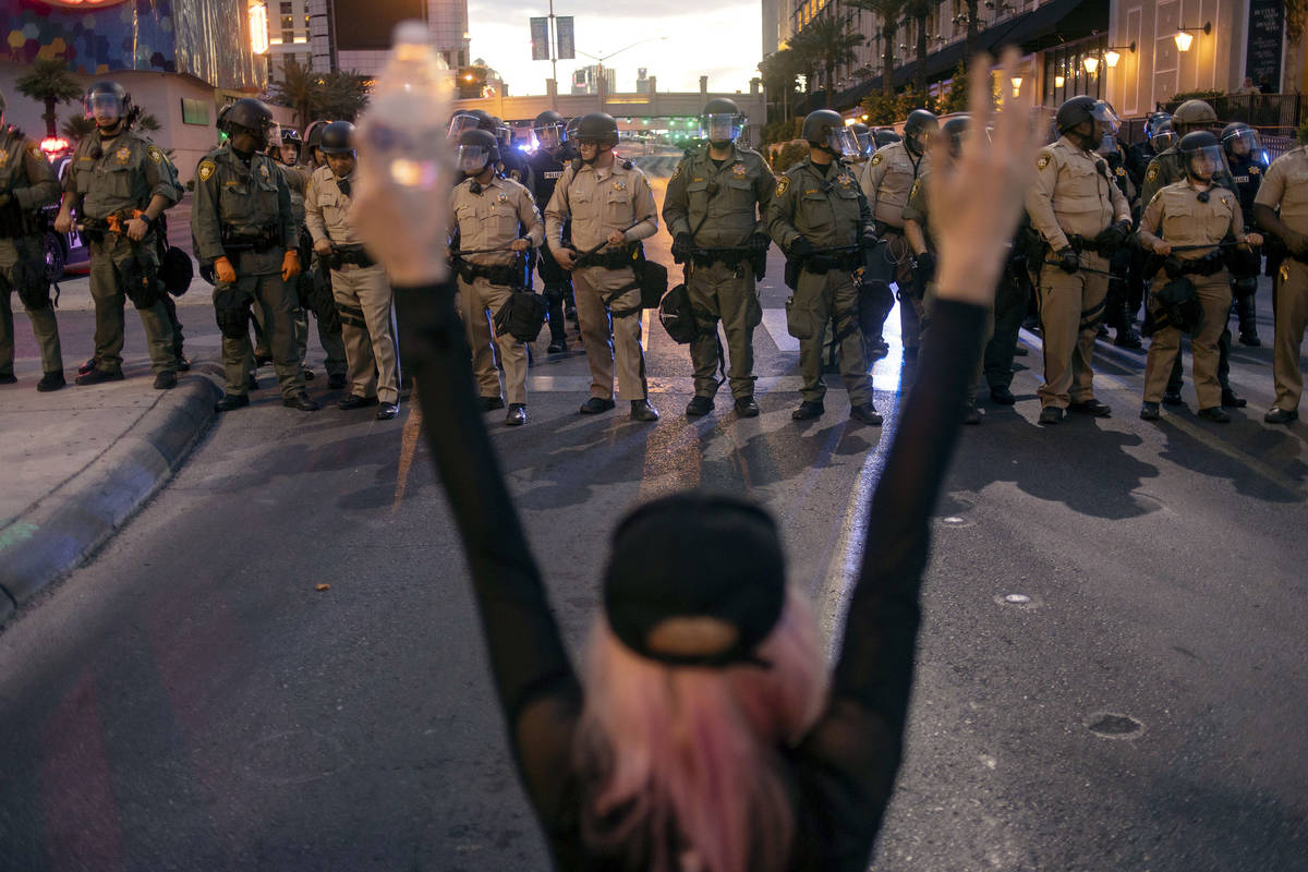 A protester chants "hands up don't shoot" at a line of Las Vegas police officers atte ...