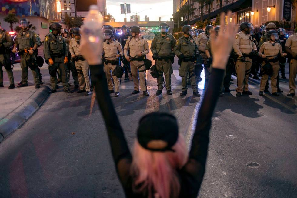 A protester chants "hands up don't shoot" at a line of Las Vegas police officers atte ...