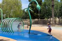 Two children running through sprinklers at Aliante Nature Discovery Park's splash pad as it reo ...