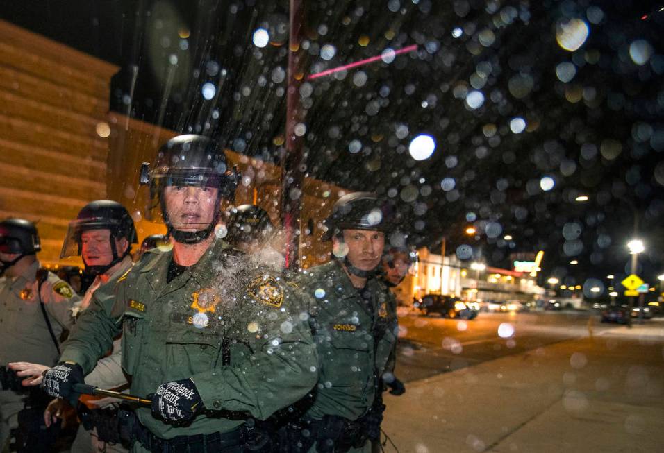 A Las Vegas Police officer is struck on the shoulder by a water bottle during clashes with prot ...