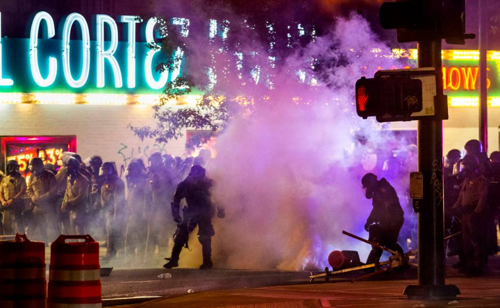 Las Vegas Police are engulfed in tear gas as protesters threw the canisters back on Fremont Str ...