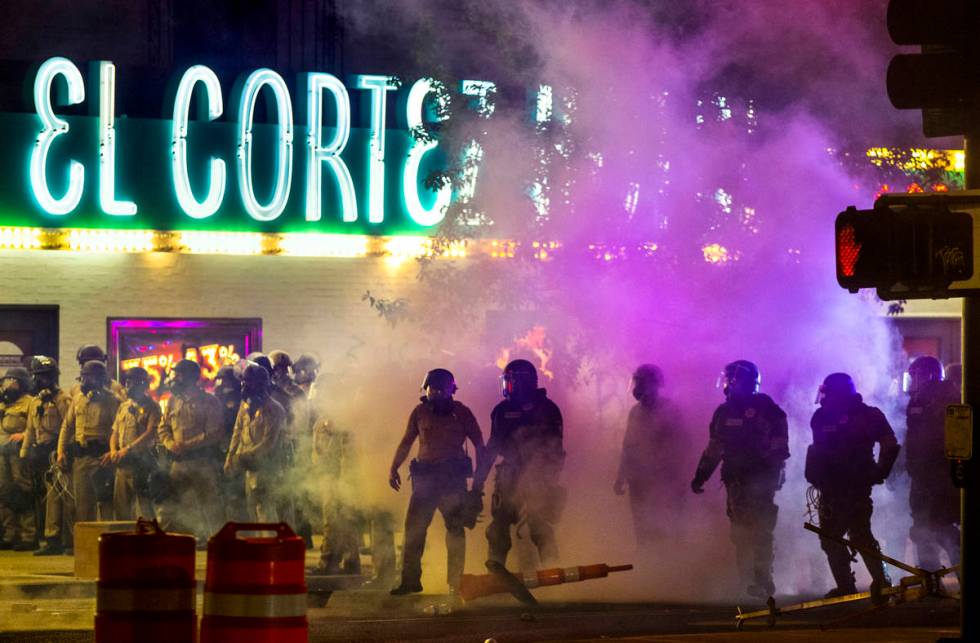 Las Vegas Police are engulfed in tear gas as protesters threw the canisters back on Fremont Str ...