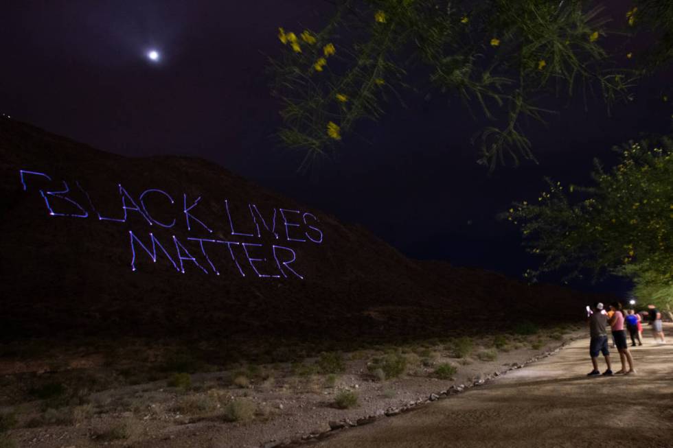 "Black Lives Matter" is projected onto the side of Lone Mountain by the company Tag Team Produc ...