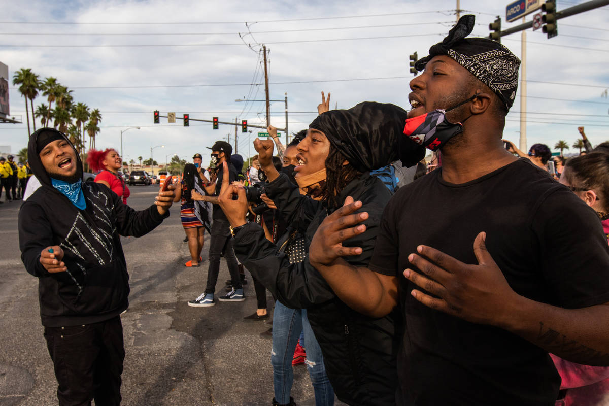 A Black Lives Matter demonstrator attempts to calm other protesters as they yell at a line of p ...