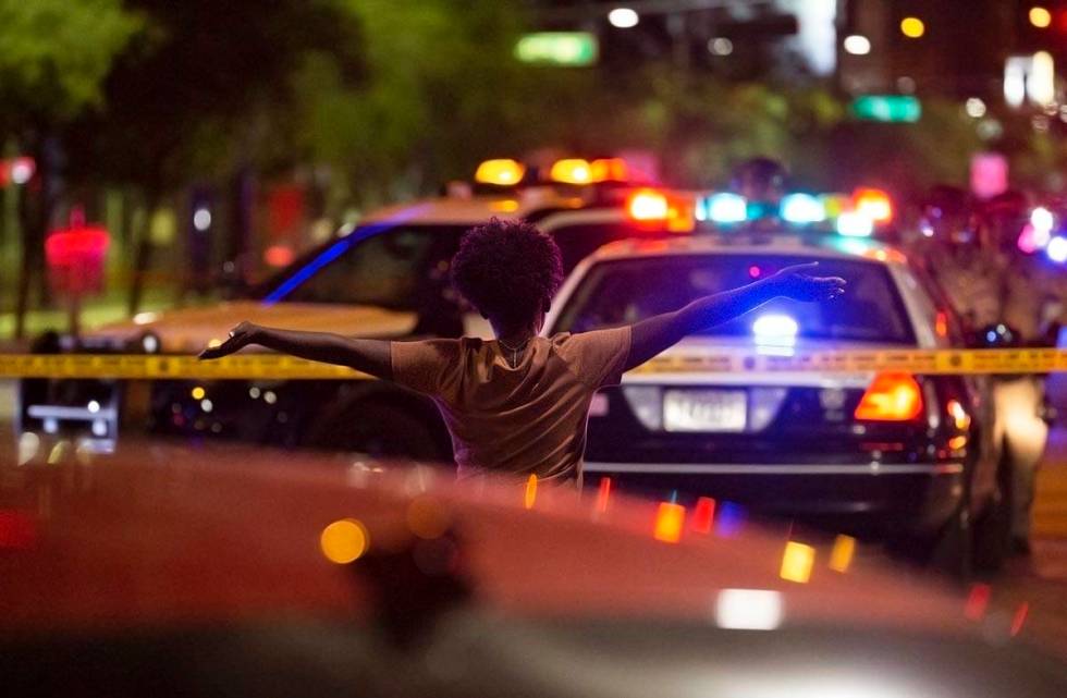 A woman walks toward police with her hands in the air after learning that a protester was shot ...