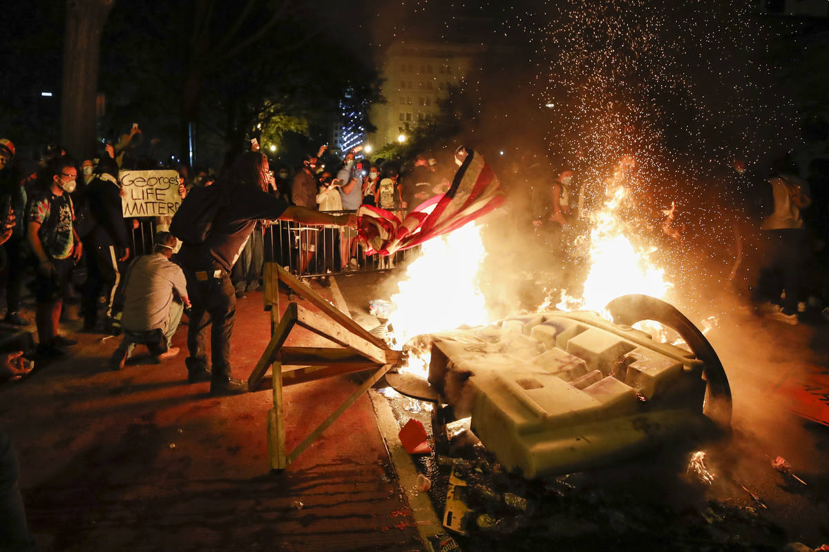 Demonstrators start a fire as they protest the death of George Floyd, Sunday, May 31, 2020, nea ...