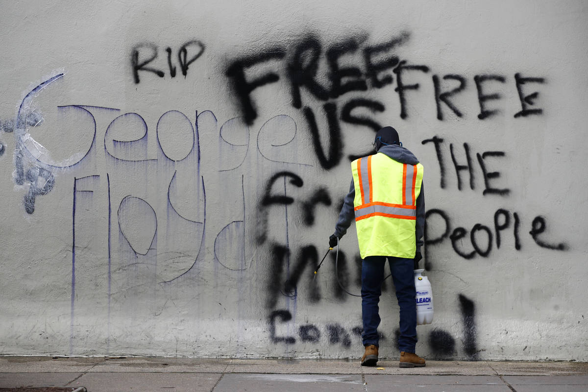 A worker removes graffiti from a building, Tuesday, June 2, 2020, in Washington, following prot ...
