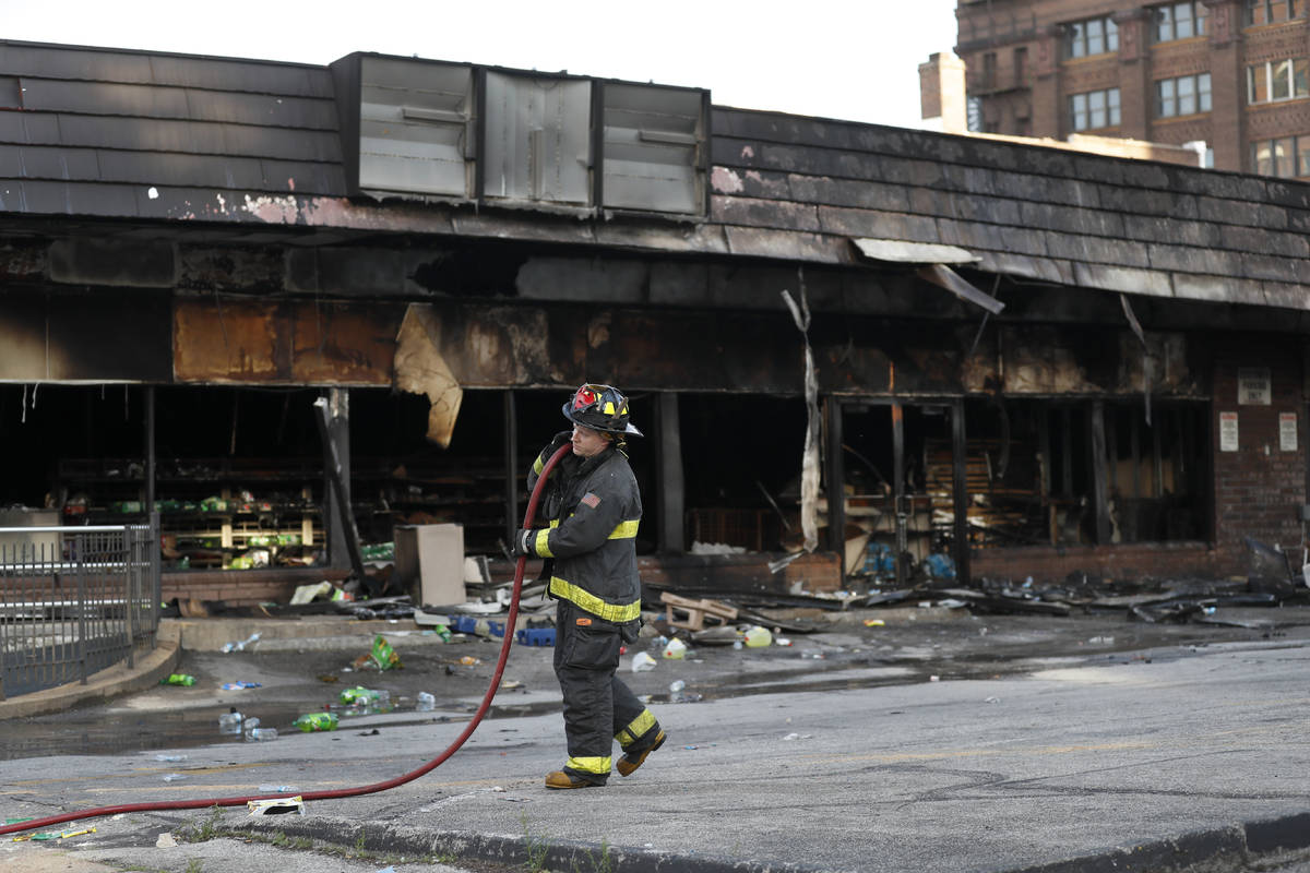 A member of the St. Louis Fire Department removes a hose outside a vandalized and burned conven ...