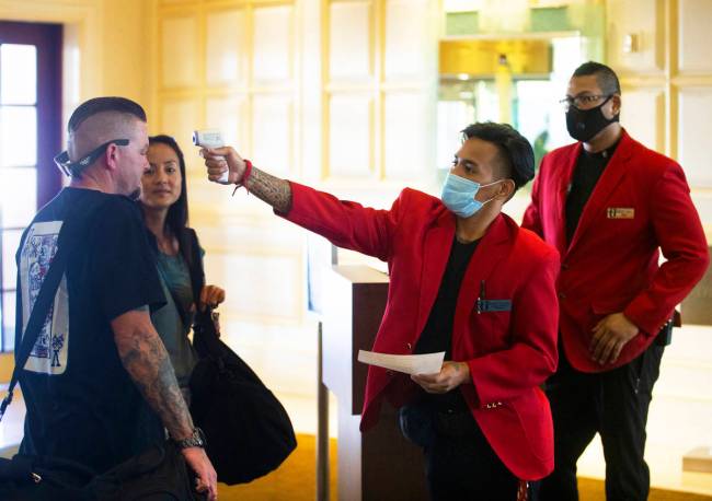 Security officers Rowell Briones, middle, and Chandler Moon, take guests temperatures before al ...