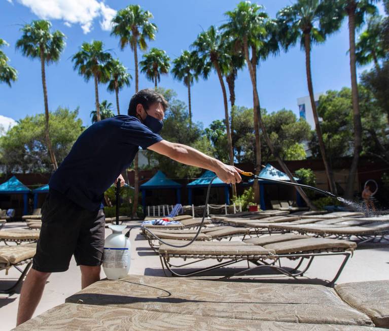 Cabana Host Cristian Elorza sprays sanitizer on pool chairs at TI on Thursday, June 4, 2020, in ...