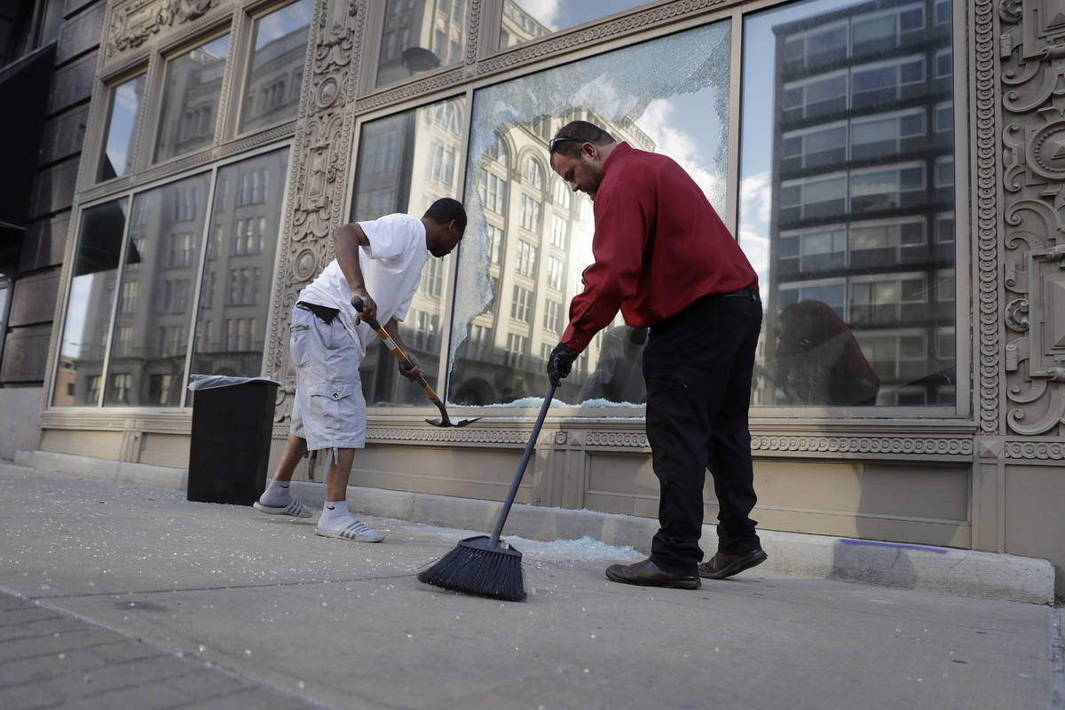 Kenneth Snelson, left, helps Dan Wilding clean up glass from a broken window, Tuesday, June 2, ...