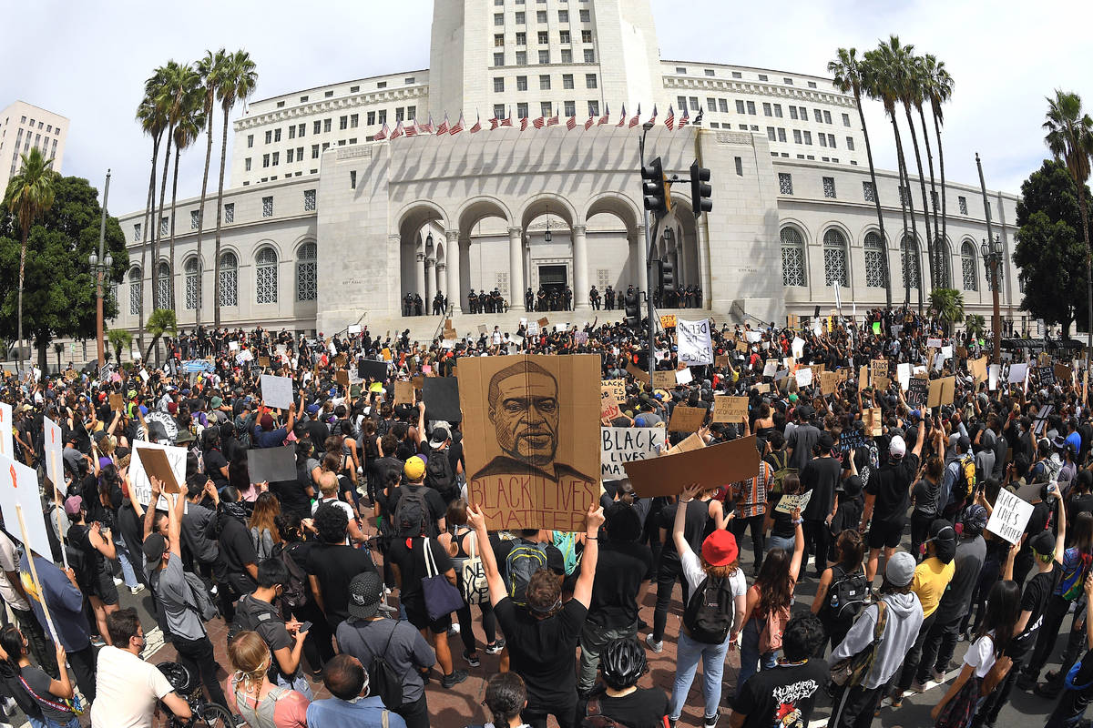 In this photo taken with a wide angle lens, demonstrators stand in front of Los Angeles City Ha ...