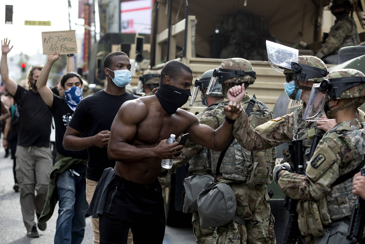 Demonstrators greet members of the National Guard as they march along Hollywood Boulevard, Tues ...