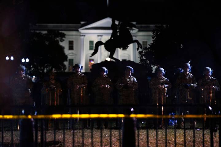 With the White House in the background, a line of police forms behind a fence in Lafayette Park ...