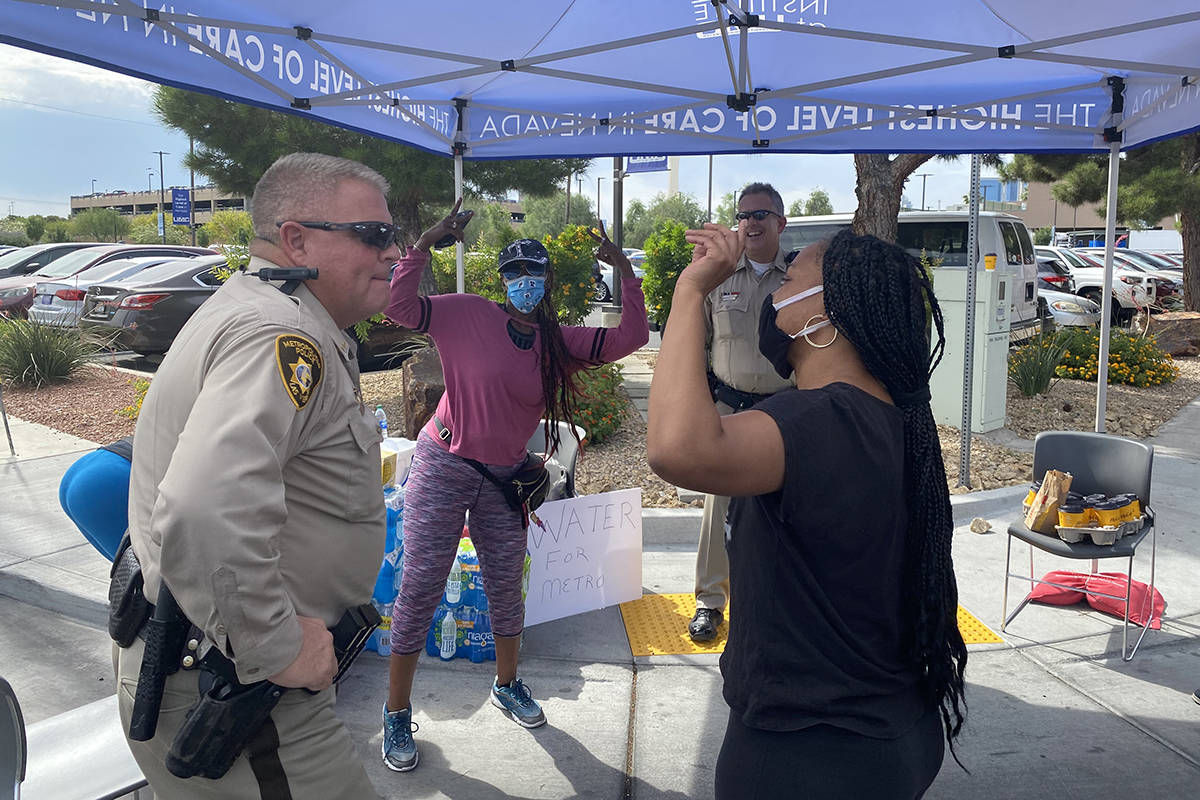 Simone Hall, right, and Demetria Williams, center, stop to thank Las Vegas police outside Unive ...