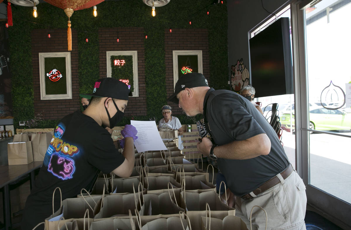 Ronald Duong, employee at Graffiti Bao restaurant, talks with Jim Lewis, a volunteer driver, wh ...