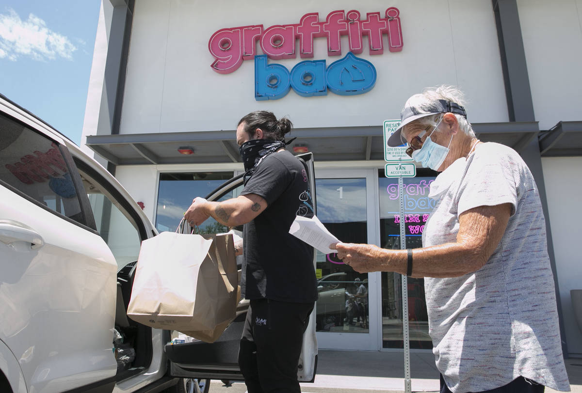Marc Marrone, chef and owner of Graffiti Bao, loads bags of food into a volunteer driver, Cecil ...