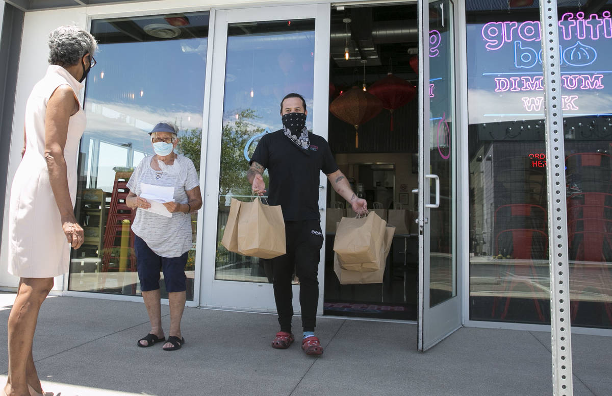 Marc Marrone, chef and owner of Graffiti Bao, carries bags of food with volunteer driver, Cecil ...