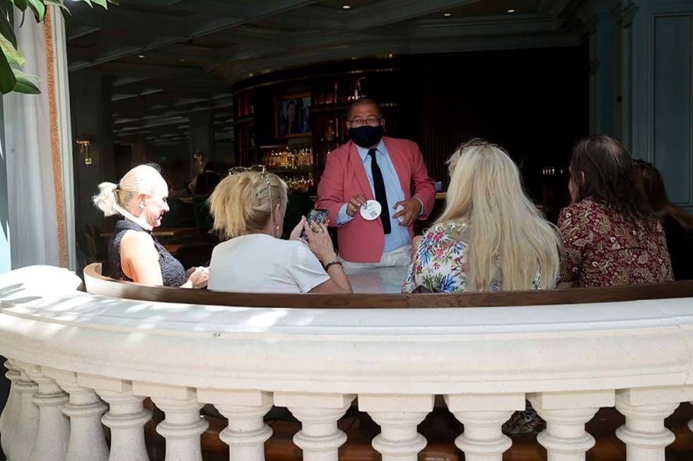 A waiter shows diners a coaster with a QR Code for the menu at Sadelle's Cafe overlooking the C ...