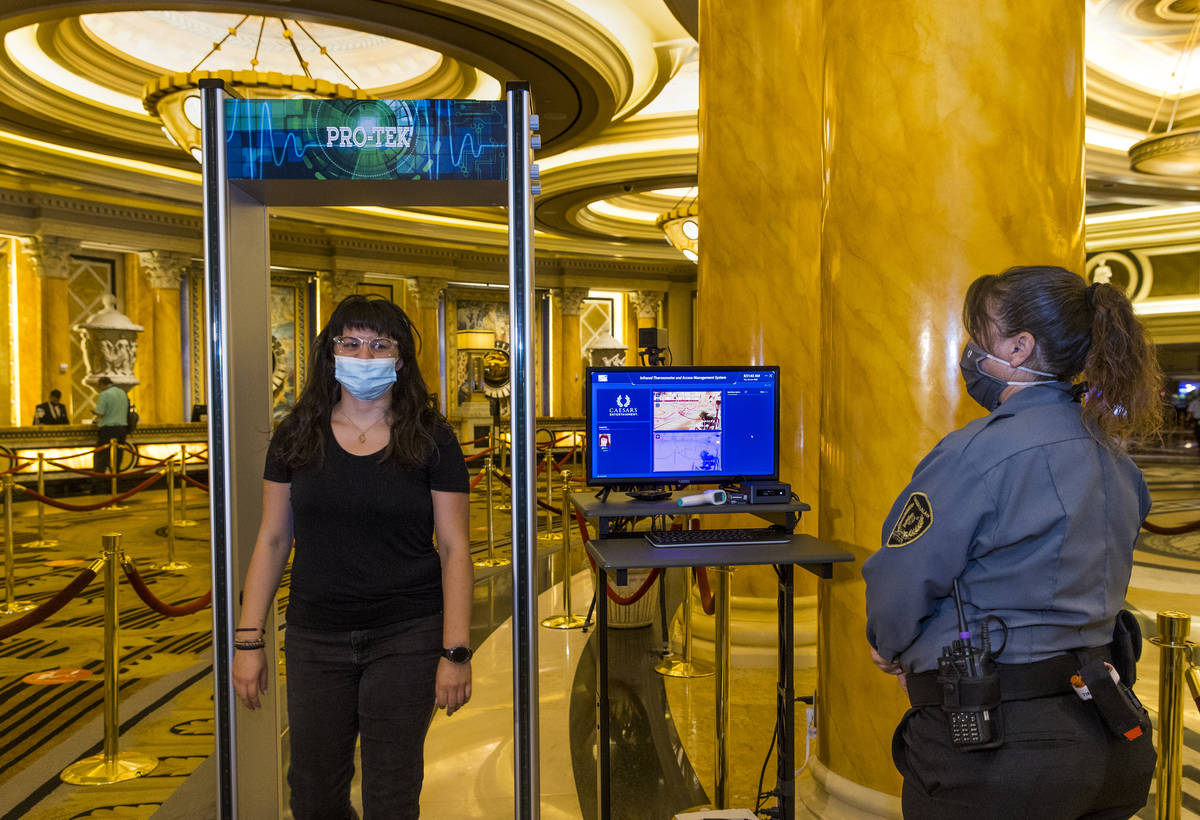 Asuka Anderson, left, walks through the infrared thermal scanner for temperature readings opera ...