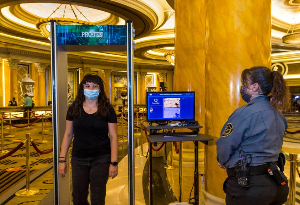 Asuka Anderson, left, walks through the infrared thermal scanner for temperature readings opera ...