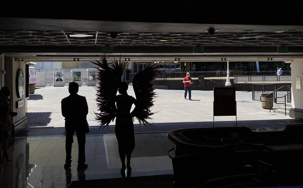 A staff member and showgirl greet guests arriving as the doors at Harrah's are open for busines ...