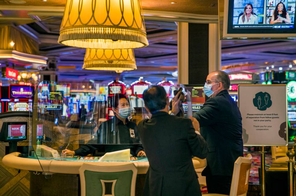 Wynn Las Vegas employees clean the plexiglass at one of their tables while Gov. Steve Sisolak t ...