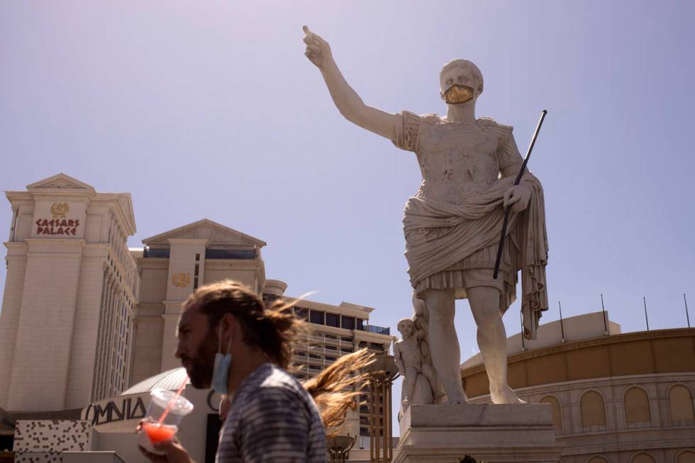 Pedestrians walk past a masked statue in front of Caesars Palace on the third day that the Stri ...