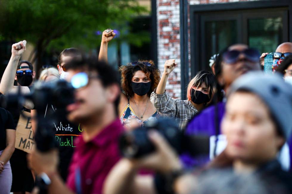 People raise their fists as the names of people killed by police are spoken during a gathering ...