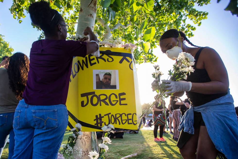 Protesters place flowers around a poster of a man killed by police during a press conference ho ...