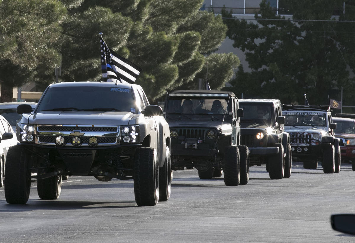 Pick up trucks and SUVs waving large American Flags drive past University Medical Center (UMC) ...