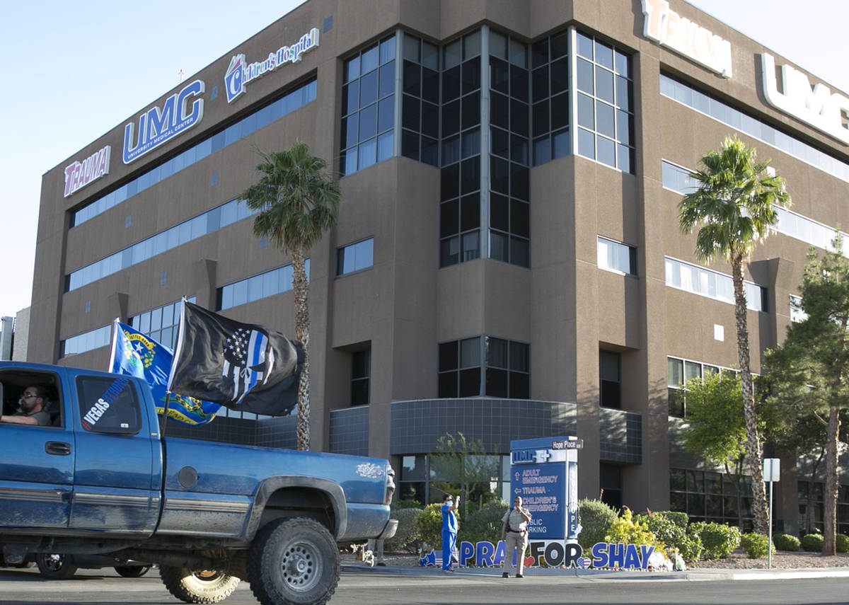 A driver in a pick up truck waving large flags drives past University Medical Center (UMC) duri ...