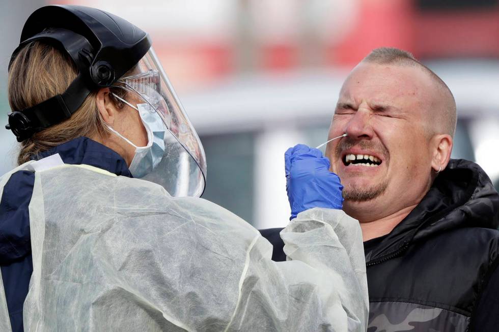 FILE - In this April 17, 2020, file photo, a man reacts as a medical staffer tests shoppers who ...