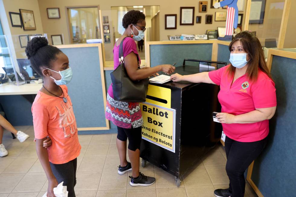 Clark County Elections worker Carmen Anaya, right, helps LaQuetha Lutale and her daughter Sanyu ...