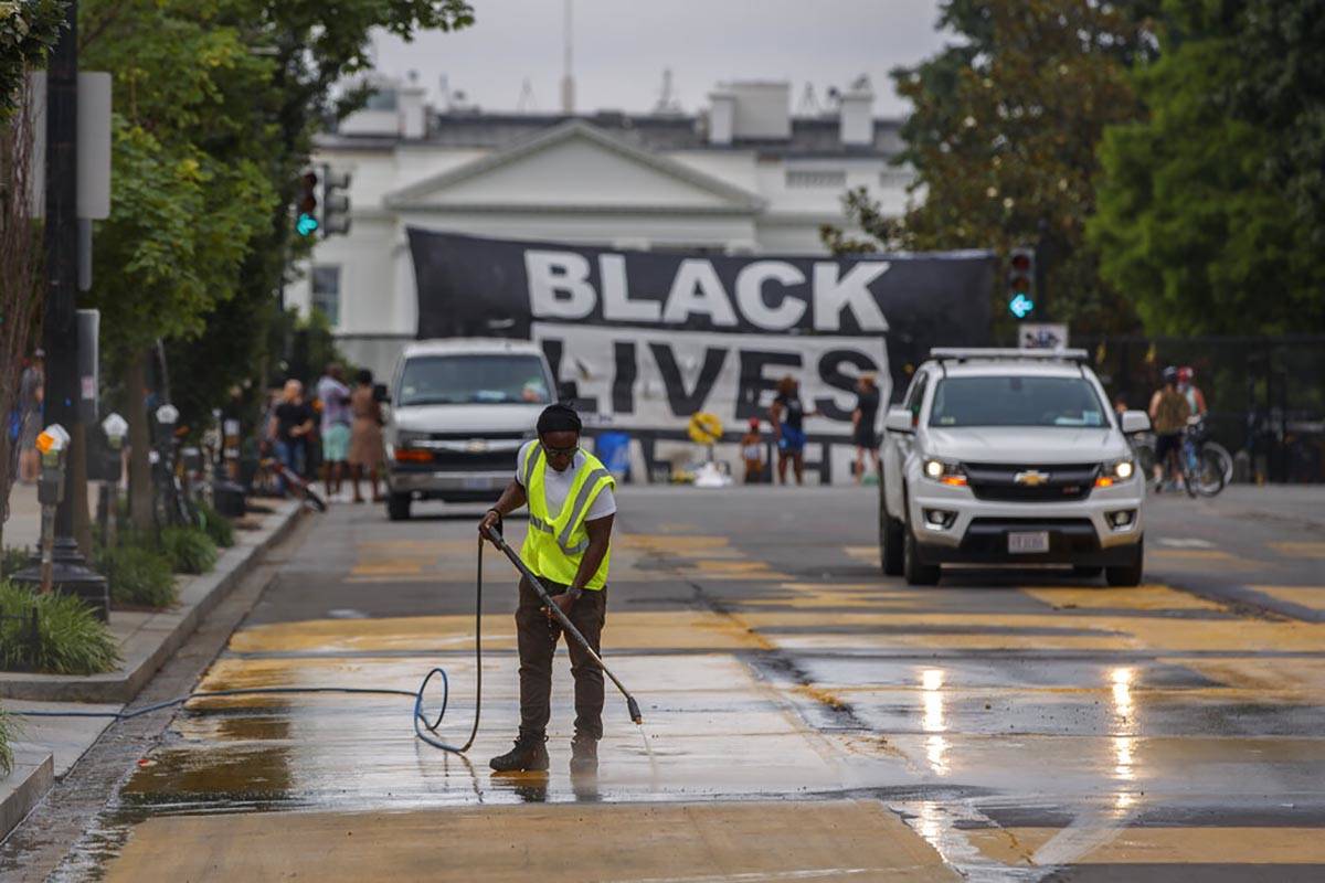 A city worker cleans the words Black Lives Matter painted in bright yellow letters on 16th Stre ...