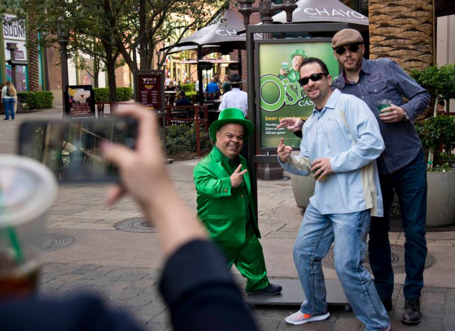 Brian Thomas, O'Sheas Casino manager and resident leprechaun, left, takes a photo with brothers ...