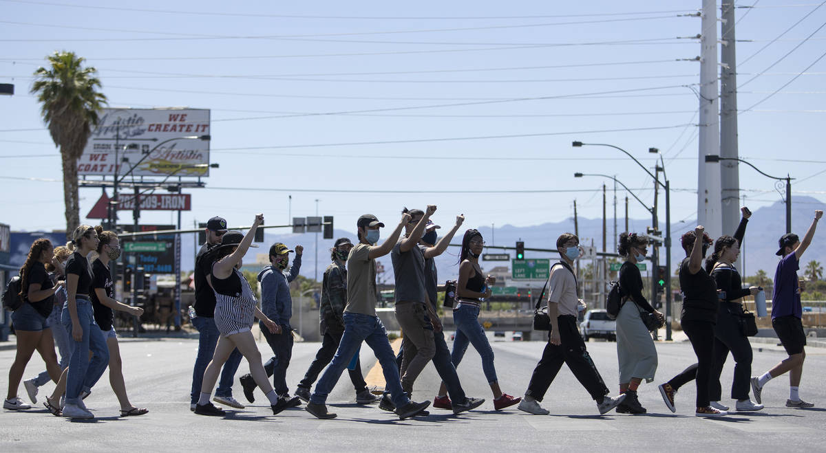 Demonstrators cross Charleston Boulevard on their way to Las Vegas City Hall in an effort to de ...