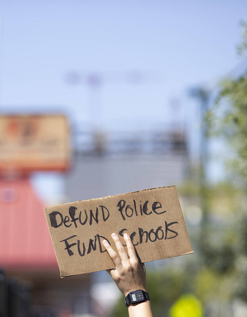One marcher carries a sign calling for local politicians to defund police and fun schools on We ...