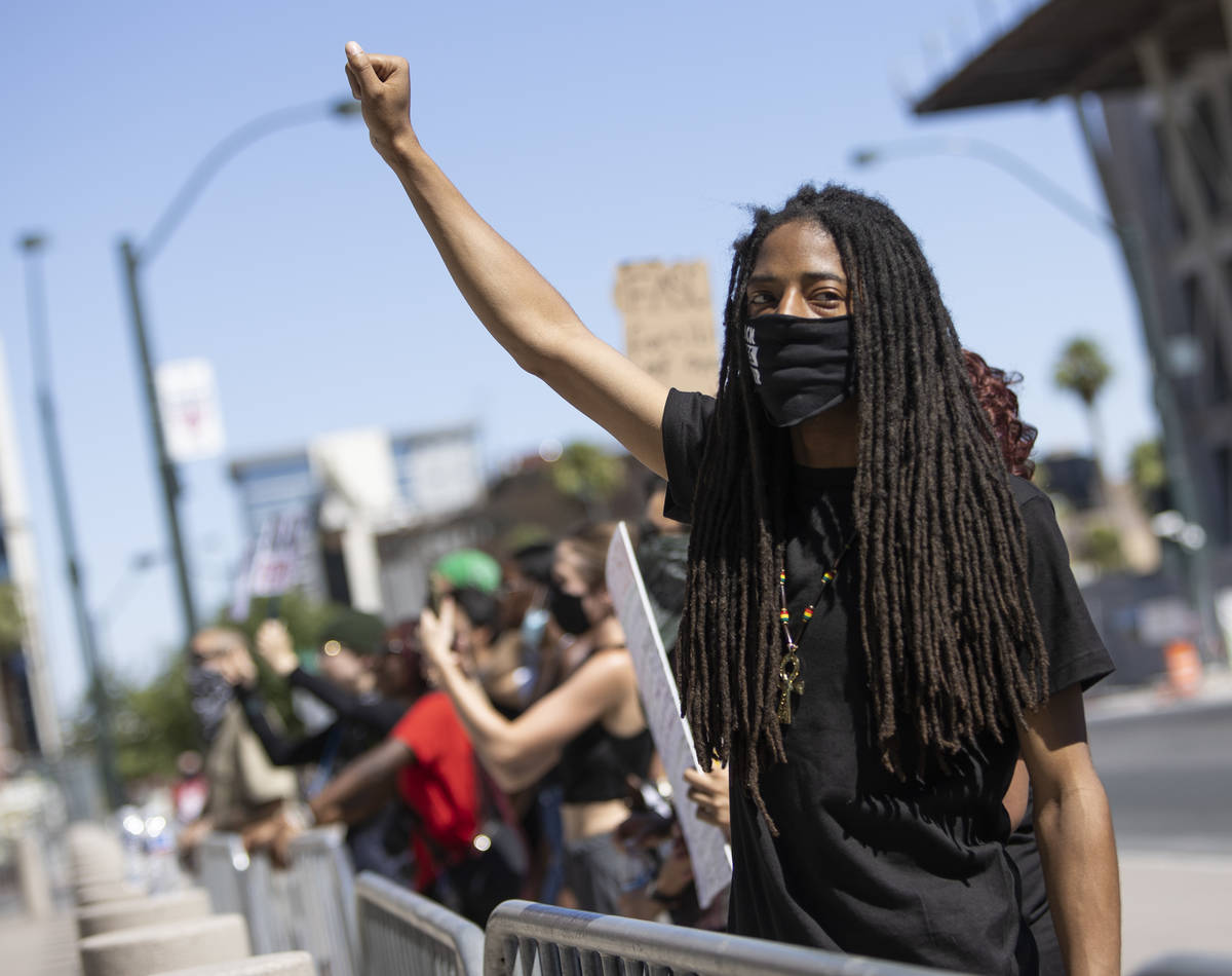 Dre Thurman holds his fist high as other protesters chant "no justice, no peace" outs ...