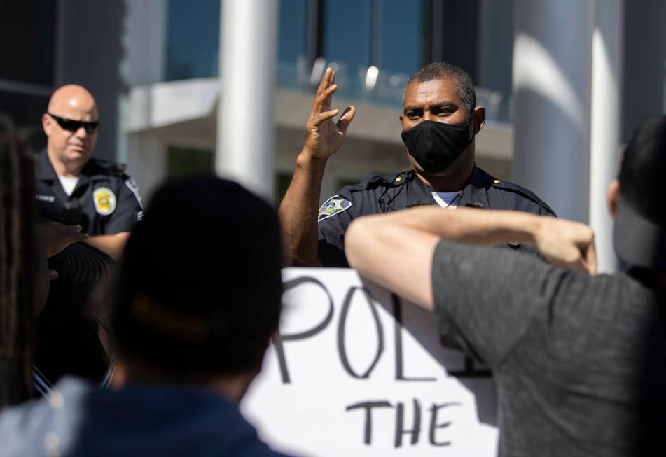 A Las Vegas police officer asks protesters, who asked to see Mayor Goodman to discuss defunding ...