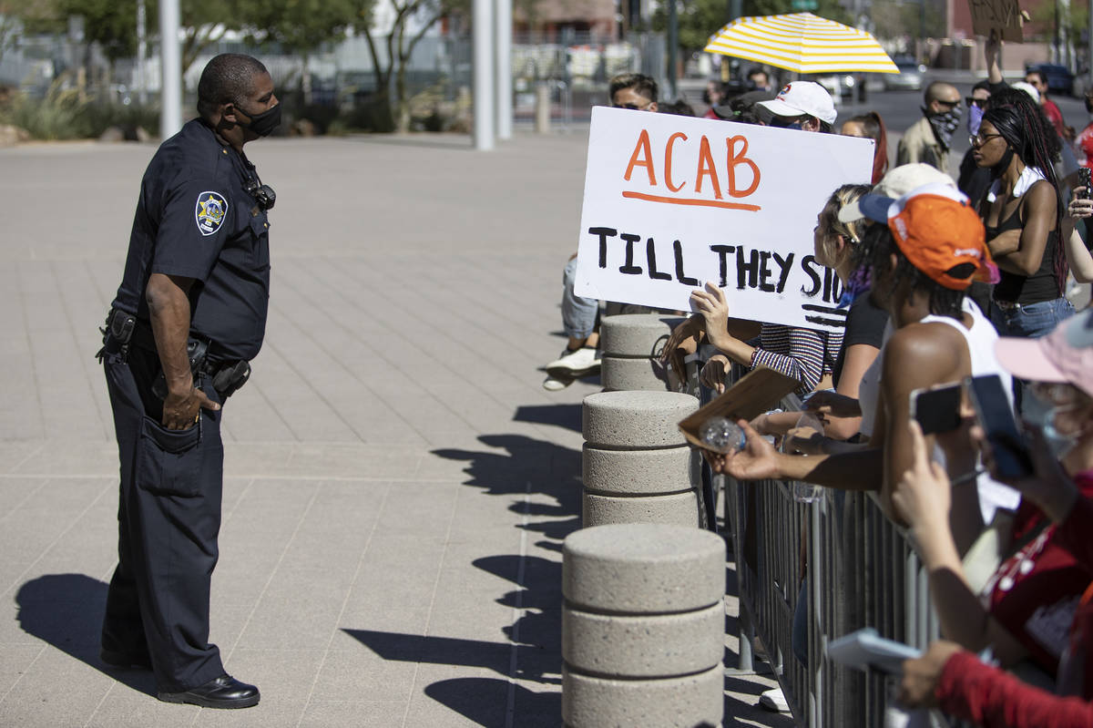 A Las Vegas police officer asks protesters, who asked to see Mayor Goodman to discuss defunding ...