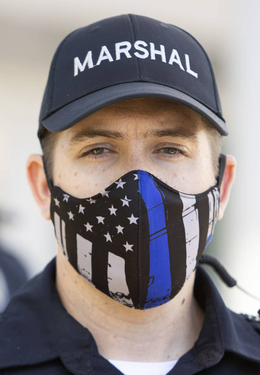 One Las Vegas police officer wears a "thin blue line" mask while standing between pro ...