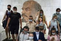 People wearing face masks to protect against coronavirus walk through the subway, with a portra ...